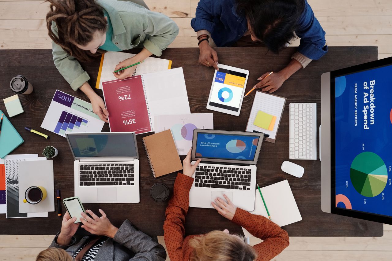 Une équipe diversifiée travaillant ensemble sur des stratégies de marketing numérique autour d’une table, avec des ordinateurs portables et des tablettes.